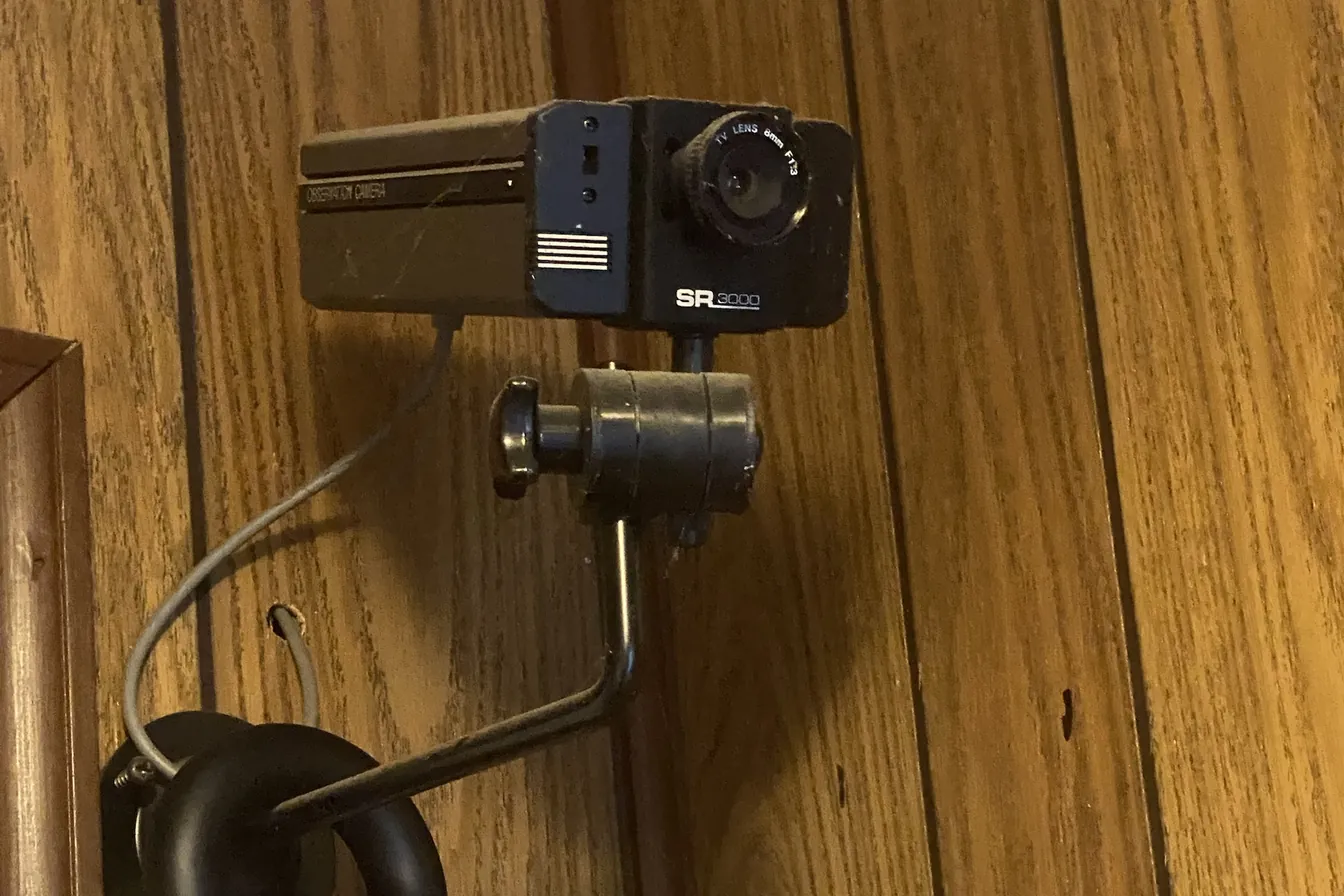 Old analog security camera mounted on a wood-paneled wall