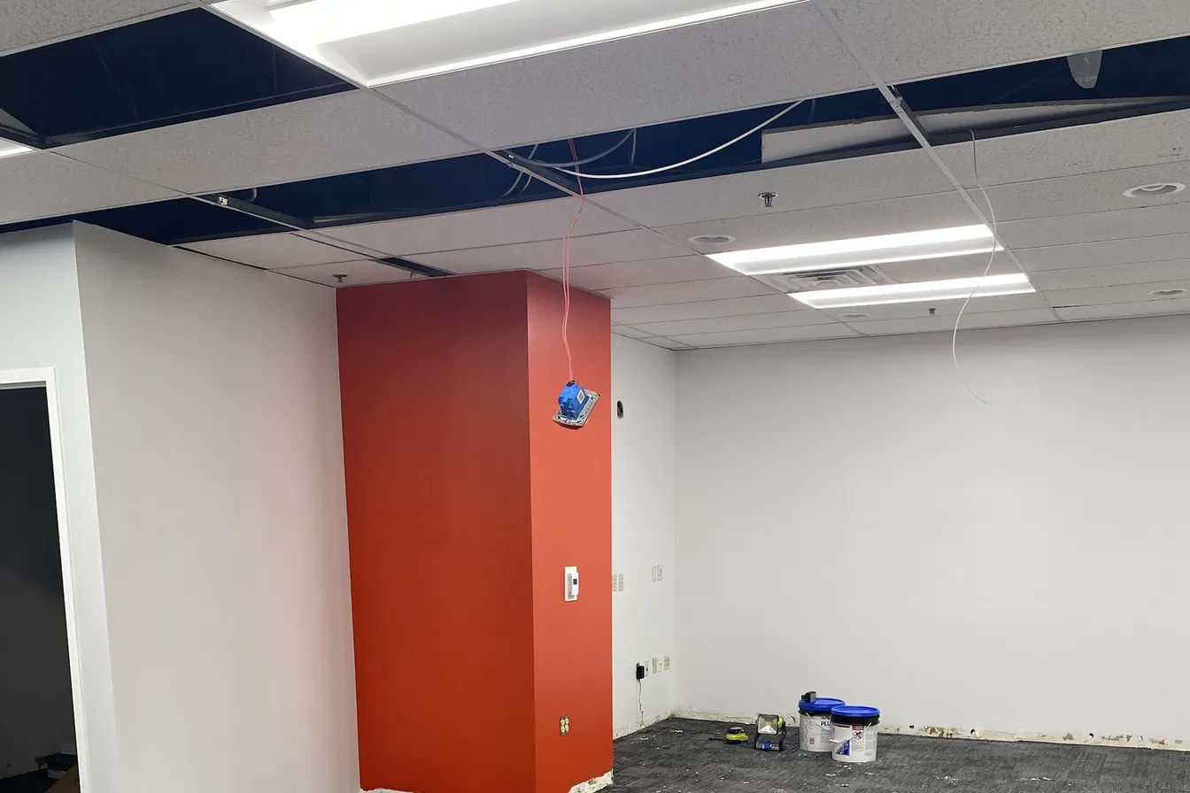 Commercial office mid-renovation with ceiling tiles out and device boxes roughed in